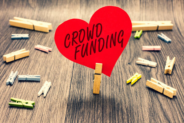 Word writing text Crowd Funding. Business concept for Fundraising Kickstarter Startup Pledge Platform Donations Clothespin holding red paper heart several clothespins wooden floor romance.