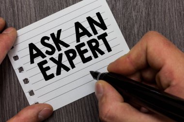 Conceptual hand writing showing Ask An Expert. Business photo showcasing Superior Reliable Ace Virtuoso Curiosity Authority Geek Man holding marker notebook page Wooden background. clipart