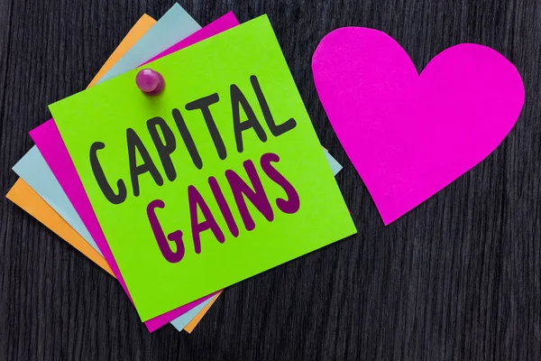 Text sign showing Capital Gains. Conceptual photo Bonds Shares Stocks Profit Income Tax Investment Funds Papers Romantic lovely message Heart Good feelings Wooden background. — Stock Photo, Image