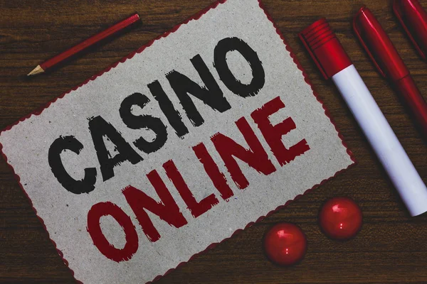 Conceptual hand writing showing Casino Online. Business photo showcasing Computer Poker Game Gamble Royal Bet Lotto High Stakes White paper red borders markers pencils wooden background.