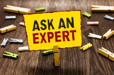 Bir uzman sormak yazma el yazısı metin. Çift güvenilir Ace virtüözü merak yetkilisi Geek birkaç clothespins ahşap zemin sarı kağıt Not tutarak Clothespin anlam kavramı.