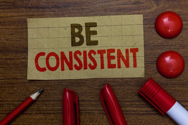 Tutarlı olmak yazma el yazısı metin. Üniforma kalıcı firma değiştirilemez bile Unchanging uyum karton işaretleri anlam kavramı ahşap arka plan fikirler kırmızı topları iletişim kalem.