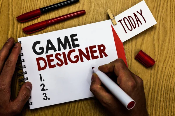 Handwriting text writing Game Designer. Concept meaning Campaigner Pixel Scripting Programmers Consoles 3D Graphics Man holding marker notebook clothespin reminder wooden table cup coffee.