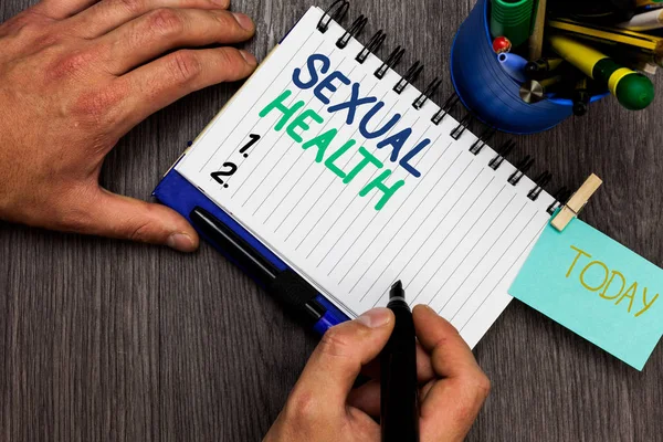 Conceptual hand writing showing Sexual Health. Business photo showcasing Healthier body Satisfying Sexual life Positive relationships Man holding marker notebook reminder cup markers wood table. — Stock Photo, Image