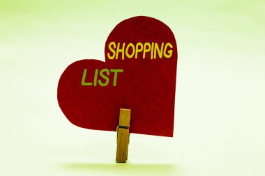 Alışveriş listesinde gösterilen Not yazma. Disiplin yaklaşımı temel öğeleri kırmızı kağıt kalp önemli romantik mesaj fikirler tutan Clothespin satın almak için alışveriş için vitrine iş fotoğraf.