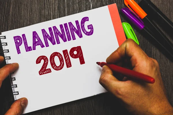 Conceptual hand writing showing Planning 2019. Business photo text Begin with end in the Mind Positioning Long term Objectives Man holding notebook paper communicating ideas Wooden background. — Stock Photo, Image