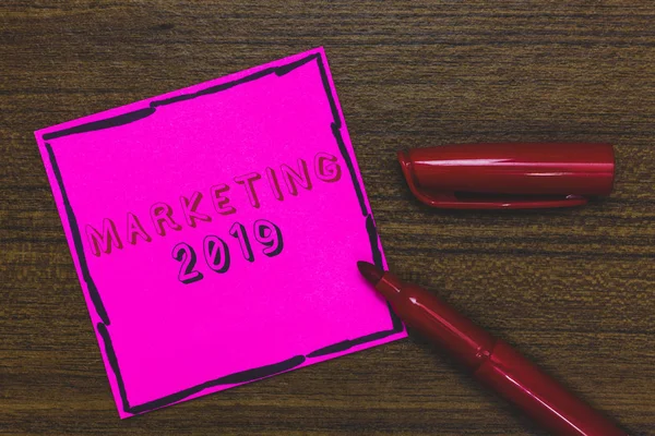 Texto de escritura a mano Marketing 2019. Concepto significado Tendencias comerciales para 2019 Evento promocional Año Nuevo Papel rosa Recordatorio importante Comunicar ideas Marcador Fondo de madera . — Foto de Stock