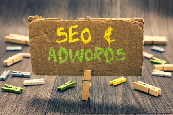 Writing note showing Seo and Adwords. Business photo showcasing Pay per click Digital marketing Google Adsense Clothespin holding paperboard important communicating message ideas. — Stock Photo, Image