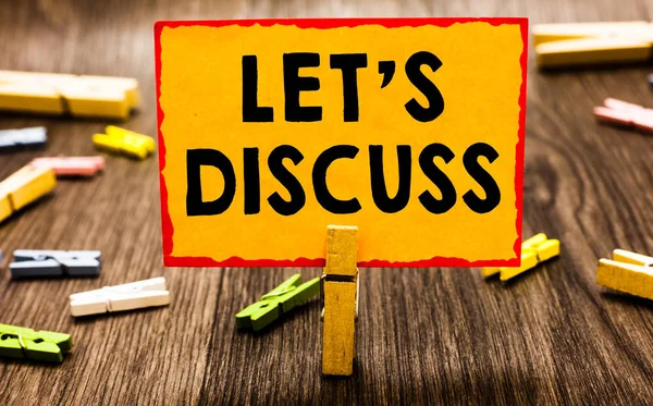 Conceptual hand writing showing Let s is Discuss. Business photo showcasing Permit to Talk Open Up Go Over a Topic Chat Sharing Clothespin holding orange paper note clothespin wooden floor.