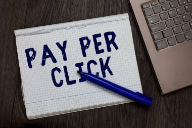Kavramsal el Pay Per Click gösterilen yazma. Sayfa siyah kalemi bilgisayar ahşap arka plan iş fotoğraf metin Internet reklam modeli arama motoru pazarlama stratejisi açık defter murabba.