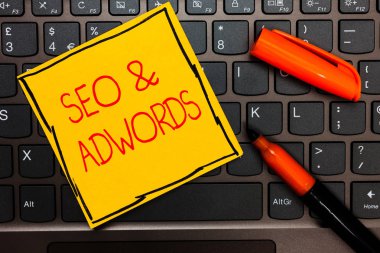 SEO ve Adwords gösterilen Not yazma. İş fotoğraf vitrine tıklama başı ödeme ilham iletişim dijital pazarlama Google Adsense sarı kağıt klavye fikirler turuncu işaretleri.
