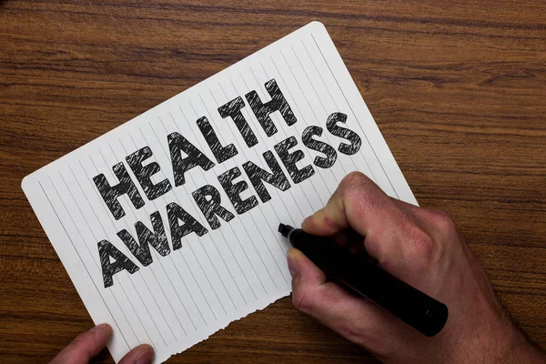Writing note showing  Health Awareness. Business photo showcasing Promoting community issues and preventative action Man holding marker notebook paper expressing ideas wooden background. — Stock Photo, Image