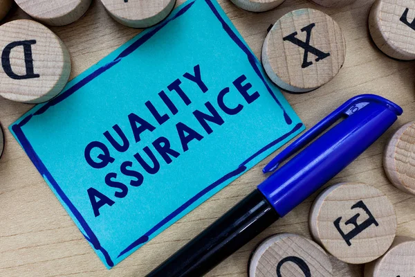 Kalite Güvencesini gösteren kavramsal el yazısı. İş fotoğrafı metni belirli bir kalitede belirlenmiş gereksinim sağlar.