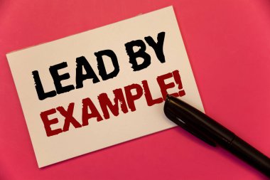 Text sign showing Lead By Example Motivational Call. Conceptual photo Leadership Management Mentor Organization Text two Words notes written note paper black pen message pink background. clipart