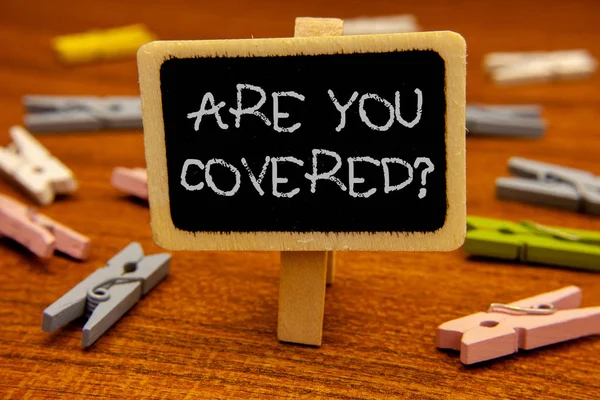 Scrivere a mano concettuale mostrando Are You Covered Question. Foto aziendale vetrina hanno una sicurezza e assicurazione sanitaria Assistenza medica Lavagna lettere gesso molletta con sfondo in legno . — Foto Stock