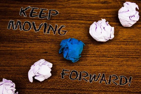 Texto de escritura de palabras Seguir avanzando Llamada motivacional. Concepto de negocio para el optimismo Progreso Persevero Mover Brown woody desktop four white crumpled paper balls central blue one . —  Fotos de Stock