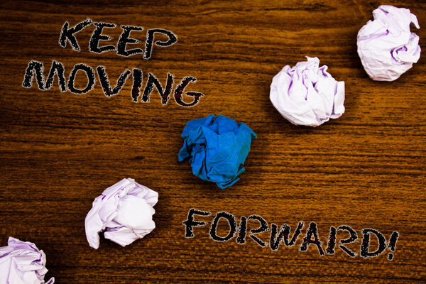 Word writing text Keep Moving Forward Motivational Call. Business concept for Optimism Progress Persevere Move Brown woody desktop four white crumpled paper balls central blue one.