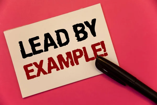 Text sign showing Lead By Example Motivational Call. Conceptual photo Leadership Management Mentor Organization Text two Words notes written note paper black pen message pink background. — Stock Photo, Image