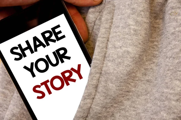 Text sign showing Share Your Story. Conceptual photo Experience Storytelling Nostalgia Thoughts Memory Personal Words written black Phone white Screen Hand holding pocket white tracksuit.