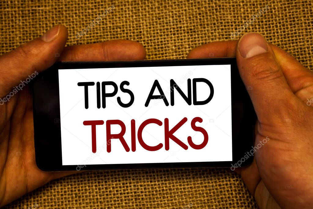 Conceptual hand writing showing Tips And Tricks. Business photo text Suggestions to Make things easier Helpful Advices Solutions Man holding cell phone screen black red letters wicker background.