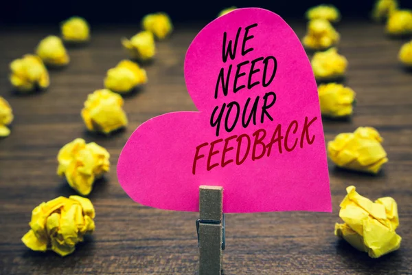 Conceptual hand writing showing We Need Your Feedback. Business photo text Give us your review thoughts comments what to improve Paperclip hold pink written heart woody floor with yellow lobs. — Stock Photo, Image