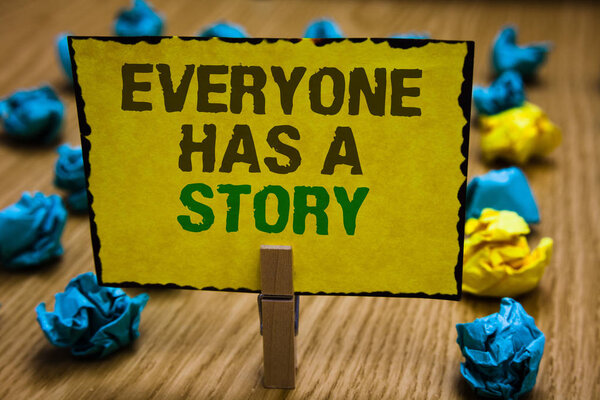 Writing note showing Everyone Has A Story. Business photo showcasing Background storytelling telling your memories tales Paperclip grip yellow page with text woody floor blue and yellow lob.