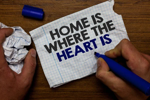 Texte d'écriture de mot Home Is When The Heart Is. Concept d'affaires pour votre maison est où vous vous sentez à l'aise et heureux Main tenir lob papier et marqueur bleu base en bois avec déchiré page blanche écrite . — Photo