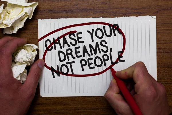 Text sign showing Chase Your Dreams, Not People. Conceptual photo Do not follow others chasing goals objectives Hand hold paper lob and red pen red circled black words on white paper.