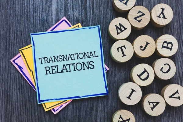Handwriting text Transnational Relations. Concept meaning International Global Politics Relationship Diplomacy Black wooden deck written sticky note beside some round woody alphabets. — Stock Photo, Image