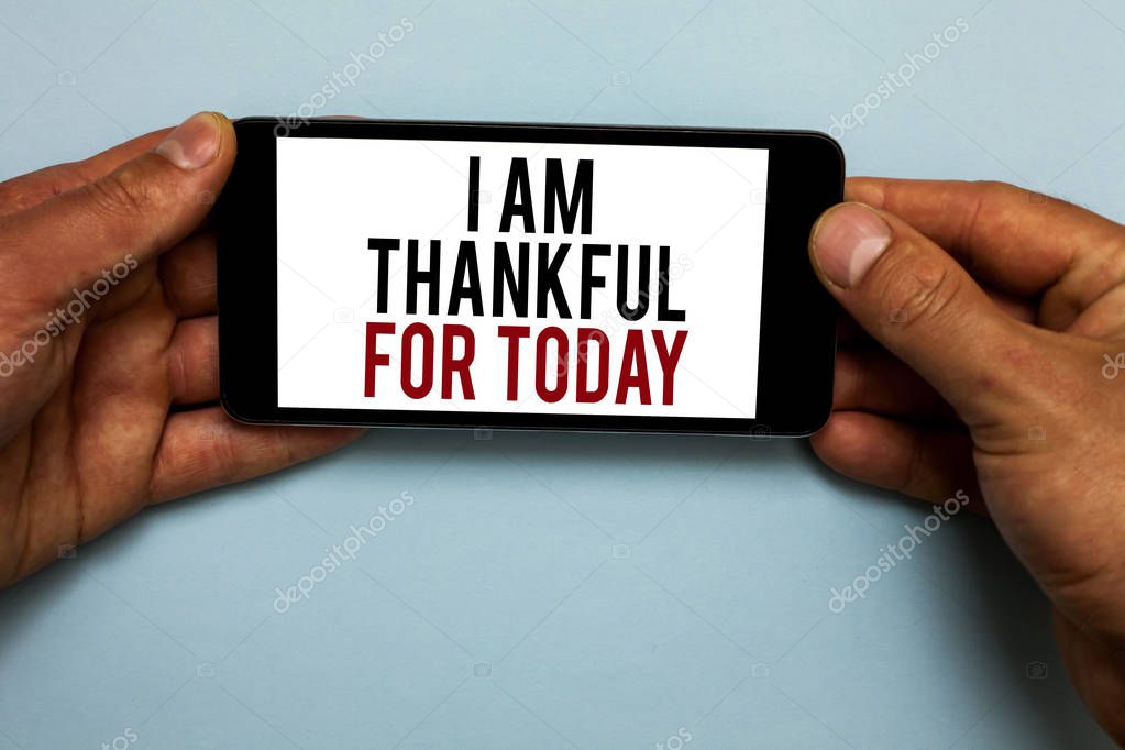 Word writing text I Am Thankful For Today. Business concept for Grateful about living one more day Philosophy Human hand hold smartphone with red and black letters on shadow blue floor.