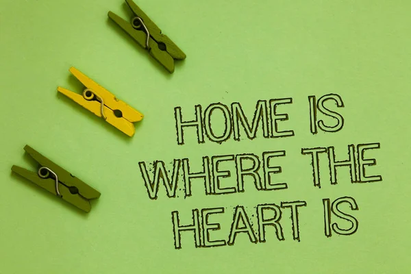 Texte d'écriture de mot Home Is When The Heart Is. Concept d'affaires pour votre maison est où vous vous sentez à l'aise et heureux Mots-clés vert milieu jaune trombone sur sol de couleur olive . — Photo