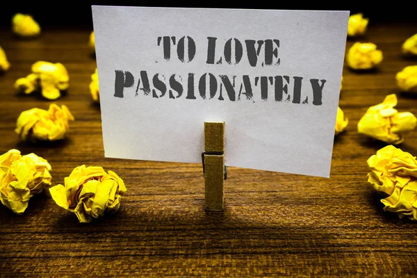 Signo de texto que muestra To Love Passionately. Foto conceptual Sentimiento fuerte para alguien o algo más Afecto Agarre del clip de papel página blanca con texto gris piso leñoso tendido lóbulo amarillo borroso . — Foto de Stock