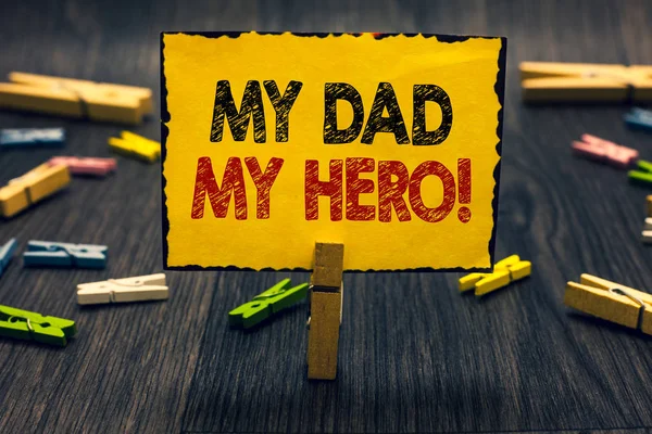Word writing text My Dad My Hero. Business concept for Admiration for your father love feelings emotions compliment Blacky wooden desk laid paper clip randomly one hold yellow board with text. — Stock Photo, Image