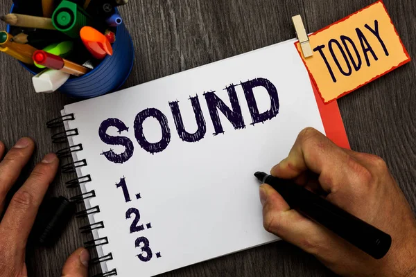 Handwriting text Sound. Concept meaning vibrations that travel through air can be heard when they reach ear Man holding marker notebook clothespin hold reminder cup markers wood table.
