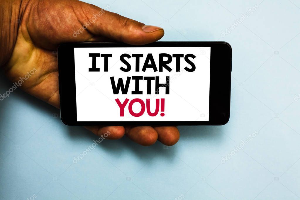 Handwriting text It Starts With You. Concept meaning Motivation for starting doing something Have discipline Human hand hold mobile phone with some black and red color letters