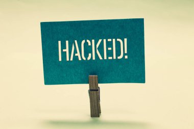 El yazısı metin Hacked. Sistem veya bilgisayar siber suç Clothespin holding turkuaz kağıt önemli verileri yetkisiz erişim anlam kavramı mesaj fikirlerini iletişim.