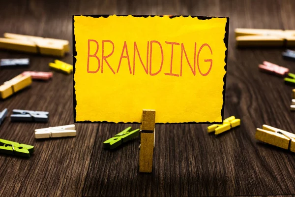 Texte manuscrit Branding. Concept signifiant Attribuer un nom de marque à quelque chose Stratégie de marketing d'entreprise Pince à linge tenant une note en papier jaune plusieurs pinces à linge plancher en bois . — Photo