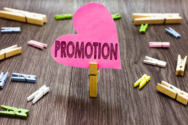 Writing note showing Promotion. Business photo showcasing Activity supporting a cause Advertising Advance in rank Sale Clothespin holding pink paper heart several clothespins wooden floor.
