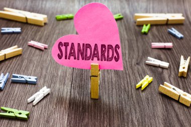 Standartları gösterilen Not yazma. Düzey kalite birkaç clothespins ahşap zemin pembe kağıt kalp tutan Clothespin takip etmek kılavuz ölçü örnek Model vitrine iş fotoğraf.