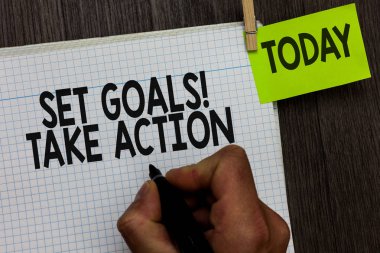 Word metin ayarla hedefleri almak eylem yazma. Hareket için iş kavramı belirli bir tarih ve açıkça dışarı atılmıştır planları adam tutarak marker defter clothespin tutun hatırlatma ahşap arka plan.