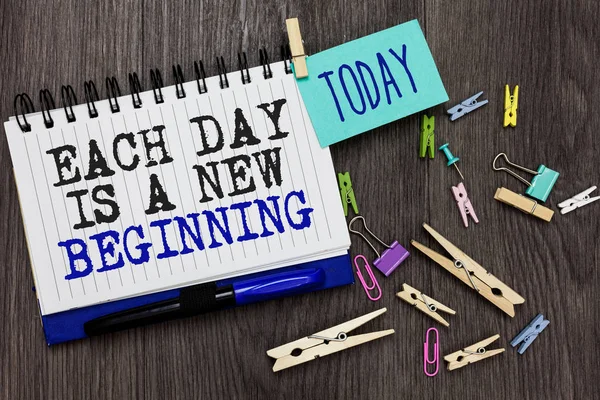 显示每一天的书写笔记是一个新的开始。商业照片展示每天早上你可以重新开始灵感不同的回形针在木质的桌子捏书面记事本蓝色笔. — 图库照片