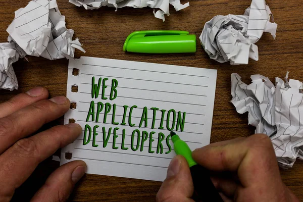 Word writing text Web Application Developers. Business concept for Internet programming experts Technology software Hand hold green pen and words on white page paper lobs around on wooden desk.