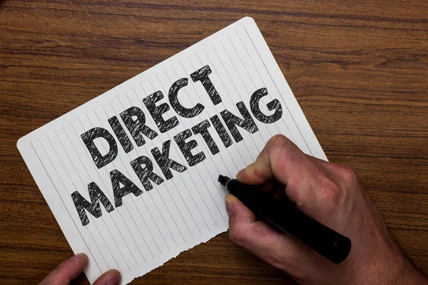 Writing note showing  Direct Marketing. Business photo showcasing business of selling products or services to public Man holding marker notebook paper expressing ideas wooden background.