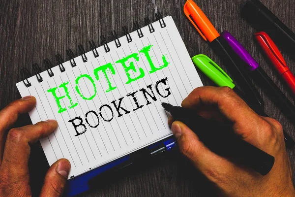 Handwriting text writing Hotel Booking. Concept meaning Online Reservations Presidential Suite De Luxe Hospitality Man holding marker notebook paper communicating ideas Wooden background.