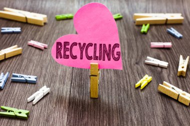 Geri dönüşüm gösterilen Not yazma. Birkaç clothespins ahşap zemin pembe kağıt kalp tutan Clothespin çevreyi korumak için yeniden kullanılabilir malzeme içine atık dönüştürme vitrine iş fotoğraf.