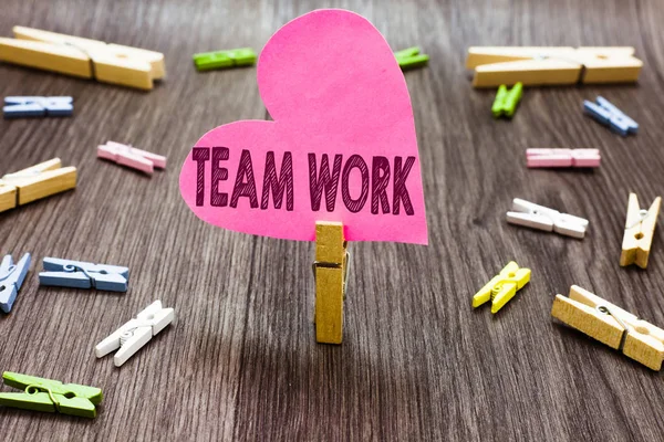 Scrivere una nota che mostri il lavoro di squadra. Business photo showcase Azione combinata di un gruppo di lavoro collaborazione collaborazione Clothespin holding rosa cuore di carta diversi mollette pavimento in legno . — Foto Stock