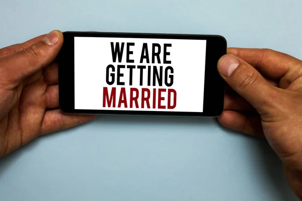 Wir heiraten. Geschäftskonzept für die Verlobung Hochzeitsvorbereitung liebende Paar menschliche Hand halten Smartphone mit roten und schwarzen Buchstaben auf Schatten blauen Boden. — Stockfoto