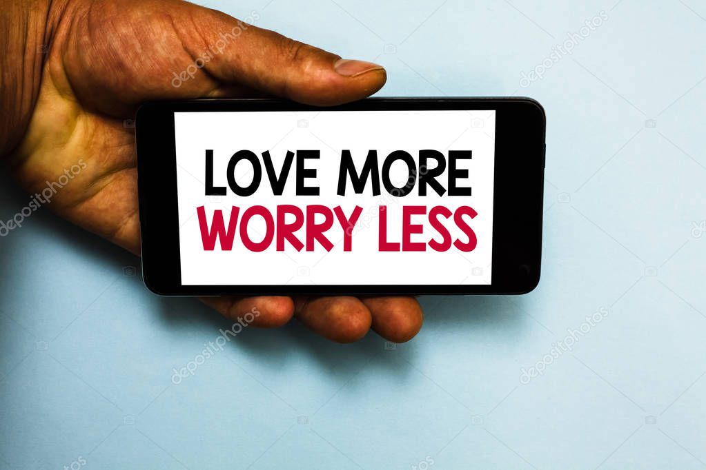 Handwriting text Love More Worry Less. Concept meaning Have a good attitude motivation be lovable enjoy life Human hand hold mobile phone with some black and red color letters.