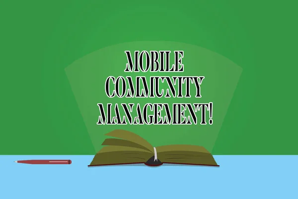 Text sign showing Mobile Community Management. Conceptual photo building relationships with online community Color Pages of Open Book photo on Table with Pen and Light Beam Glaring.