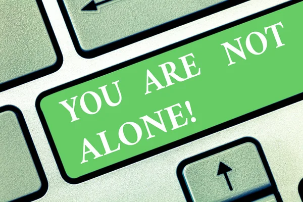 Writing note showing You Are Not Alone. Business photo showcasing Offering help support assistance collaboration company Keyboard key Intention to create computer message pressing keypad idea.